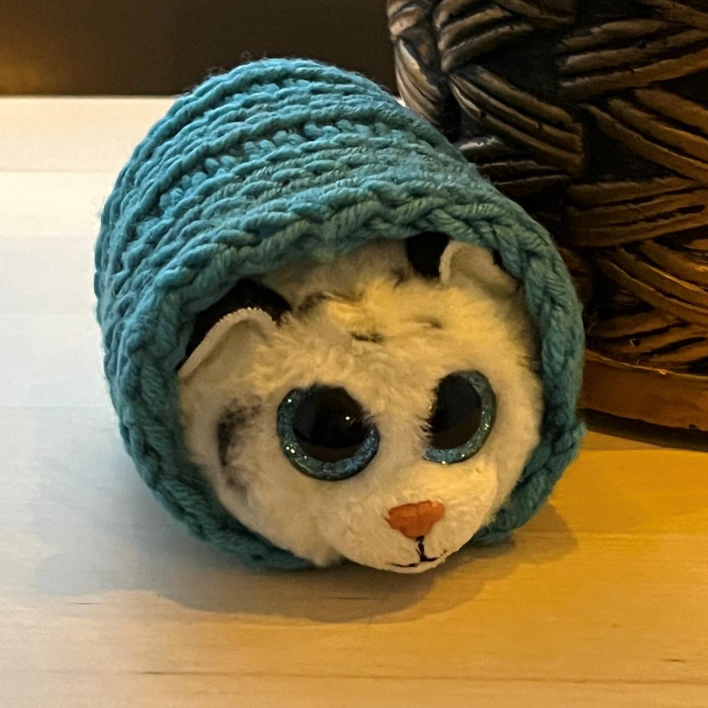 A plushy cat toy wrapped in a knitted mini-coat