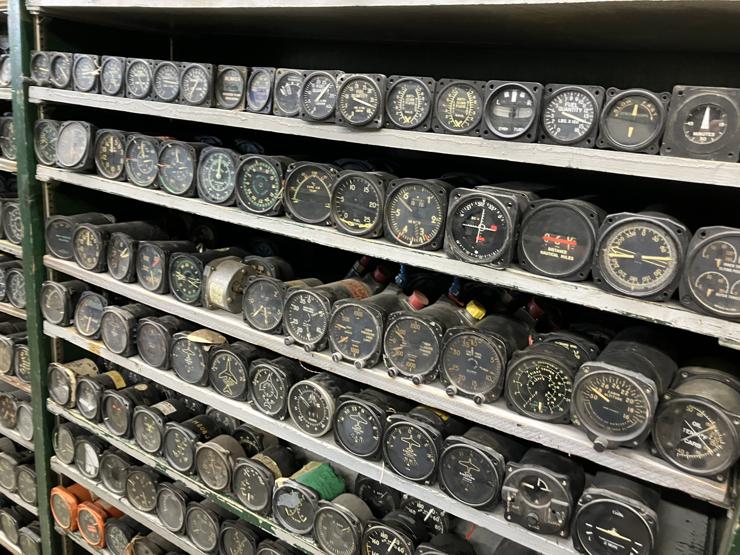 Several shelves full of analog gauges, mostly from airplanes.