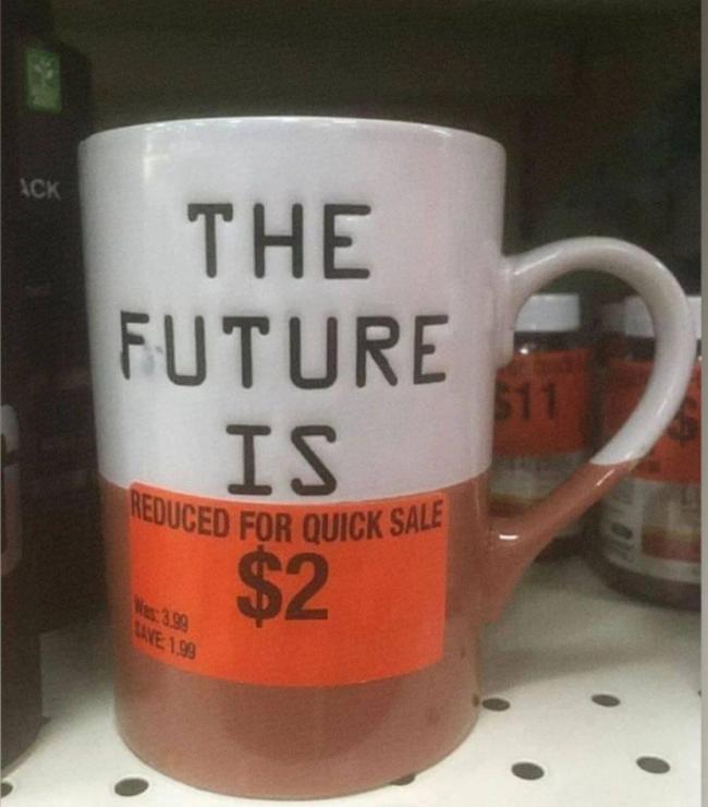 A photo of a mug with words “The future is”. Last word is covered with sticker from the shop saying “Reduced for quick sale”